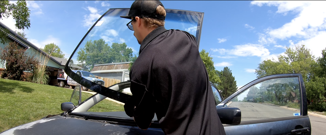 Auto glass technician performing a windshield replacement service to a car